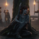 Ellie in The Last of Us Part II, hiding from enemies behind a tree at night.